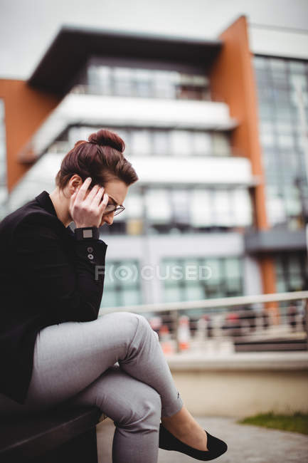 Tensed businesswoman sitting against building — Stock Photo