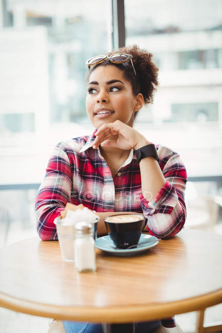 Продумана молода жінка сидить за столом у ресторані — стокове фото