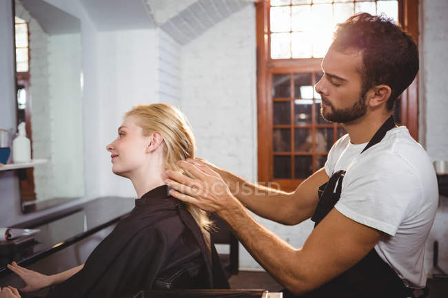 Handsome hair stylist styling woman hair in salon — Stock Photo