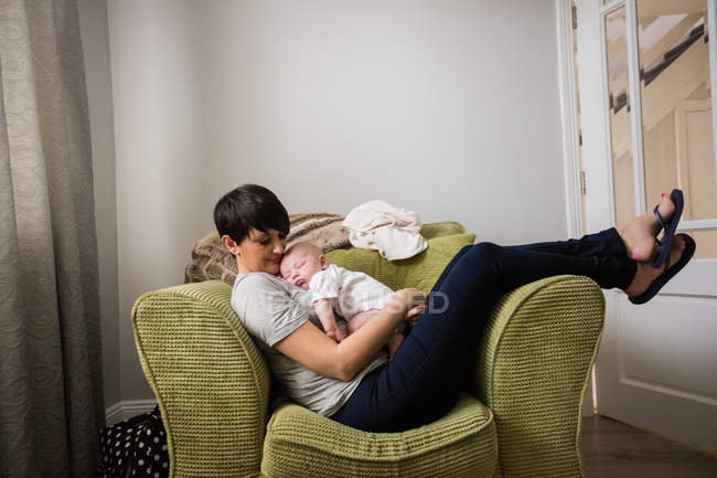 Mãe segurando bebê enquanto dormia na sala de estar em casa — Fotografia de Stock