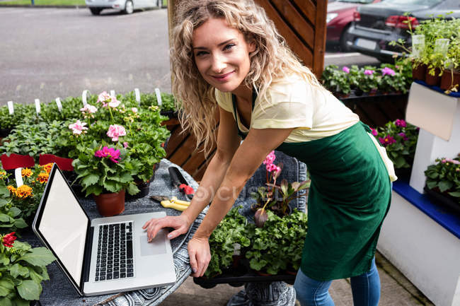 Ritratto di fiorista femminile con computer portatile nel centro del giardino — Foto stock