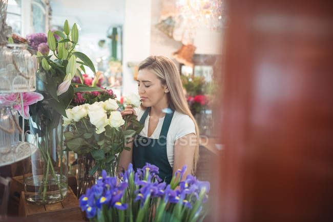 Fleuriste femelle sentant la fleur à sa boutique de fleurs — Photo de stock