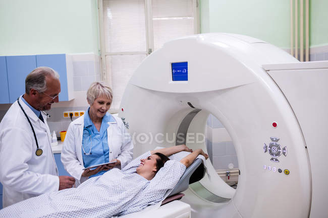 Médicos que interactúan con el paciente en la sala de exploración del hospital - foto de stock