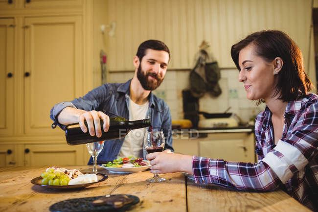 Uomo versando vino in bicchiere a donna a casa — Foto stock