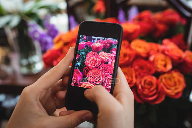 Mains de fleuriste femelle prenant des photos de fleurs dans la boutique de fleurs — Photo de stock