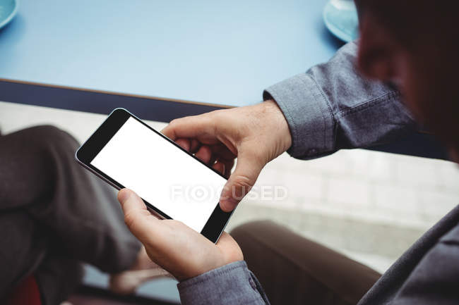 Cropped image of man text messaging on mobile phone in cafeteria — Stock Photo