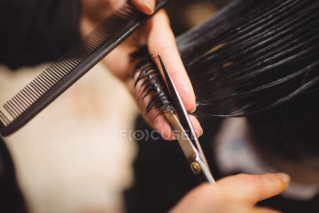 Man getting his hair trimmed with scissors in barber shop — Stock Photo