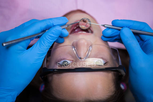 Дантист осматривает молодого пациента с помощью инструментов в стоматологической клинике — стоковое фото