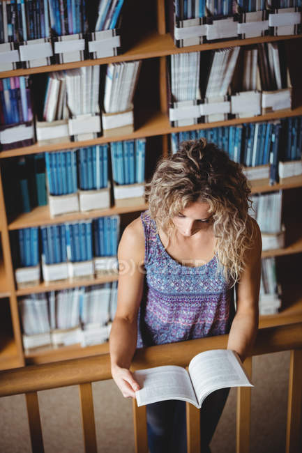 Beautiful woman reading book in library — Stock Photo