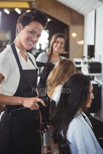 Mulheres recebendo cabelos secos com secadores de cabelo no salão de cabeleireiro — Fotografia de Stock