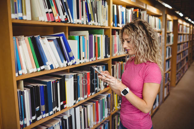 Frau benutzt Handy in Bibliothek — Stockfoto