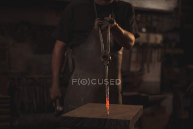 Mittelteil des Schmieds mit rotem Metallstab und Zange bei der Arbeit — Stockfoto