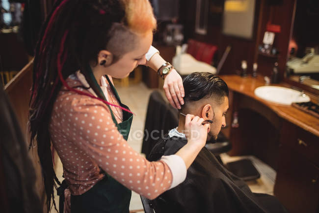 Man getting his hair trimmed with razor in barber shop — Stock Photo