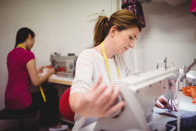 Diseñadoras de moda femeninas trabajando en el portátil en el estudio - foto de stock