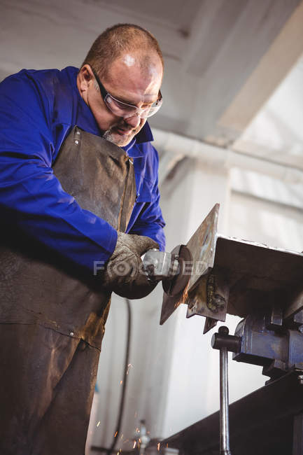 Сварщик распиливания металла с электрическим инструментом в мастерской — стоковое фото