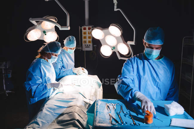 Chirurgien prenant des ciseaux du plateau pendant l'opération — Photo de stock
