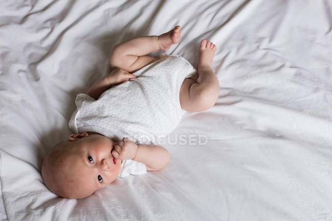 Закройте восхитительного ребенка, лежащего на кровати дома — стоковое фото