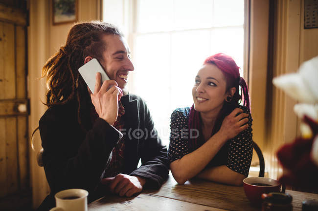 Homem falando ao telefone enquanto sentado por mulher em casa — Fotografia de Stock