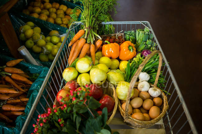 Variety of vegetables and fruits in shopping cart in supermarket — Stock Photo