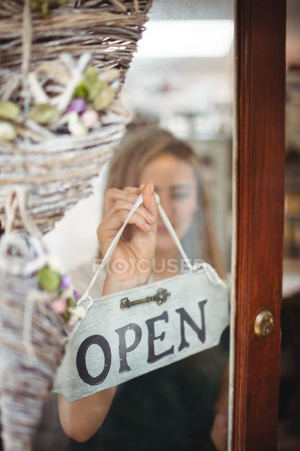 Fleuriste femelle tenant un panneau ouvert dans la boutique de fleurs — Photo de stock