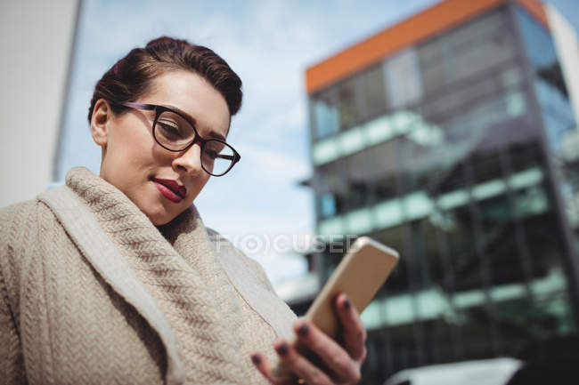 Beautiful woman using mobile phone by building — Stock Photo
