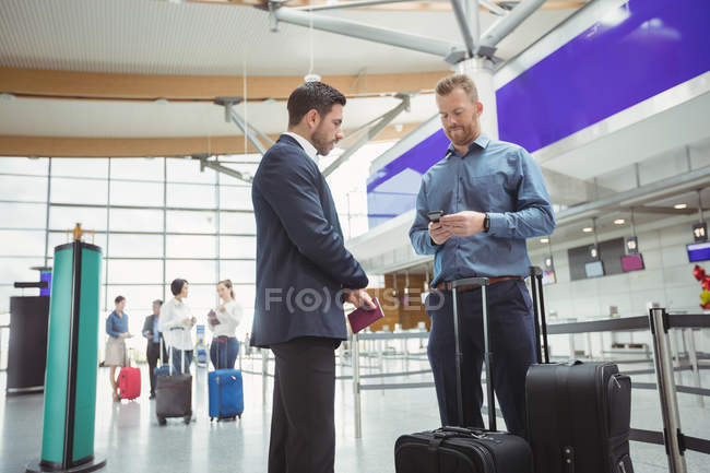 Business people waiting at check-in counter with luggage in airport terminal — Stock Photo