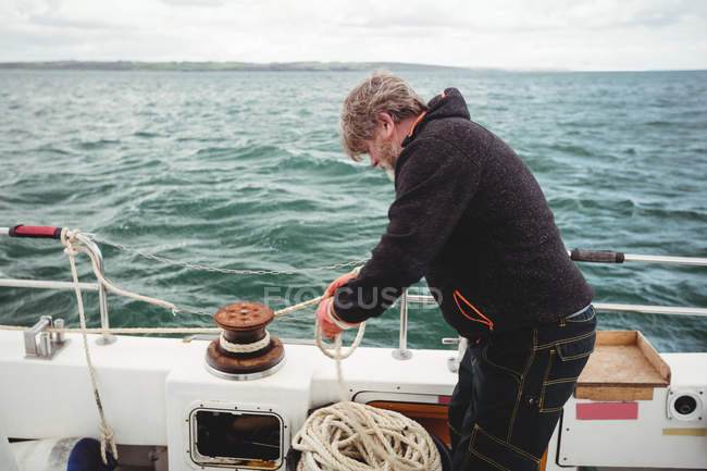 Рибалка зав'язує мотузку на боларді в човні — стокове фото