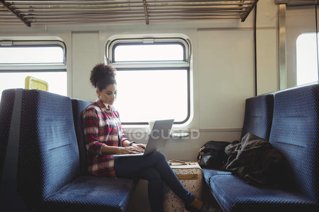 Femme utilisant un ordinateur portable tout en étant assis dans le train — Photo de stock