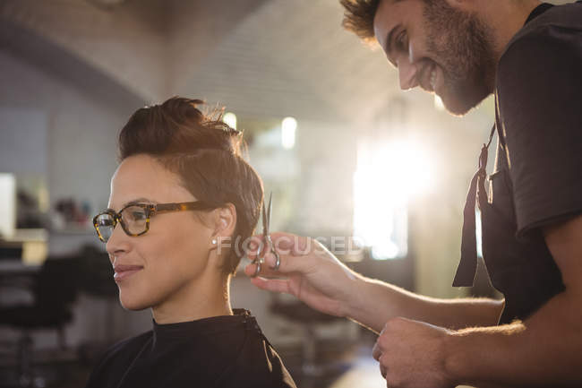 Mujer consiguiendo su pelo recortado en salón - foto de stock