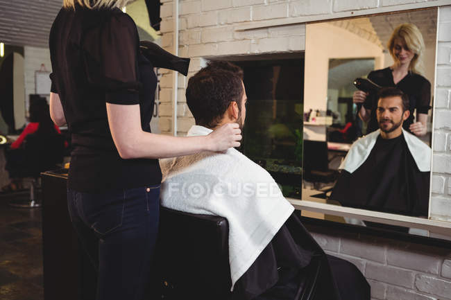Мужчина высушивает волосы феном в салоне — стоковое фото