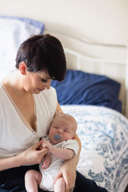 Baby mit Attrappe schläft zu Hause auf dem Arm der Mutter — Stockfoto
