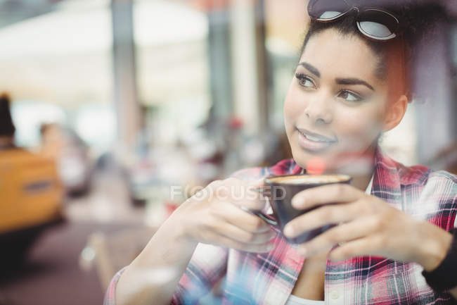 Primer plano de la joven reflexiva tomando café en el restaurante - foto de stock