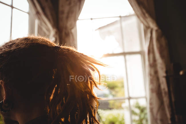 Imagem cortada de hipster por janela em casa — Fotografia de Stock