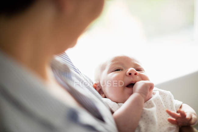 Imagem cortada da mãe segurando seu bebê em casa — Fotografia de Stock