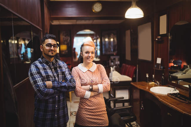 Portrait of two barbers standing with arms crossed in barber shop — Stock Photo