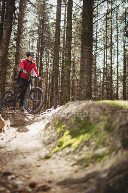 Чоловічий гірський велосипедист з велосипедом серед дерев у лісі — стокове фото