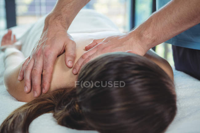 Physiotherapist giving physical therapy back of female patient in clinic — Stock Photo