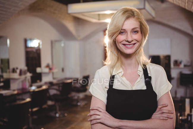 Portrait de coiffeuse debout avec les bras croisés au salon — Photo de stock