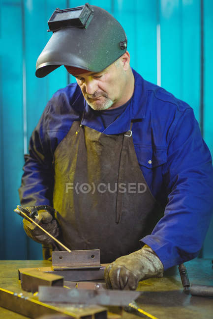 Soldador macho trabajando en pieza de metal en taller - foto de stock