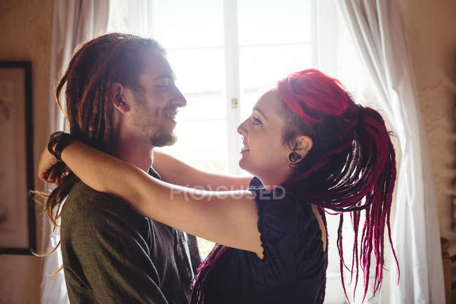 Giovane coppia hipster in piedi contro la finestra a casa — Foto stock