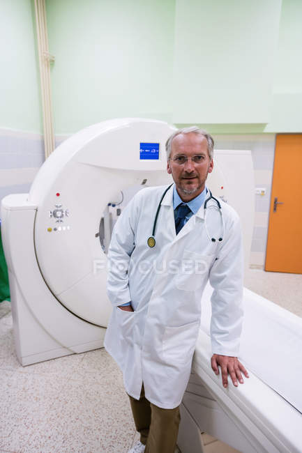 Porträt eines Arztes, der neben einem MRI-Scanner im Krankenhaus steht — Stockfoto