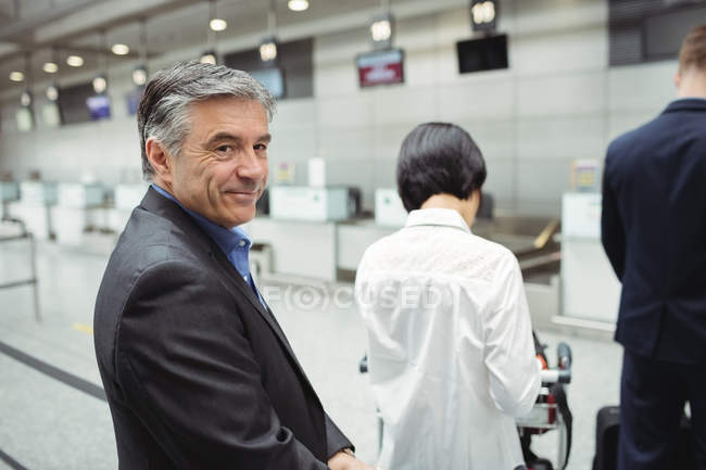 Бизнесмен, стоящий в очереди у стойки регистрации с багажом в аэропорту — стоковое фото