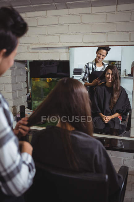 Усміхнена жінка-перукар, що працює на клієнта в перукарні — стокове фото