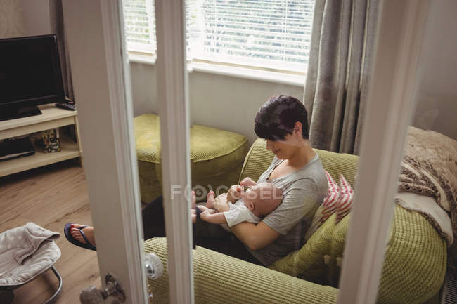 Mère nourrissant son bébé dans le salon à la maison — Photo de stock