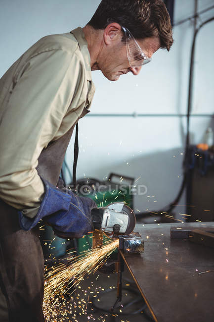 Сварщик резки металла с электрическим инструментом в мастерской — стоковое фото