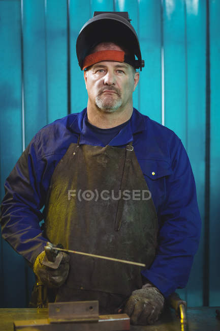 Male welder holding welding arch in workshop and looking at camera — Stock Photo
