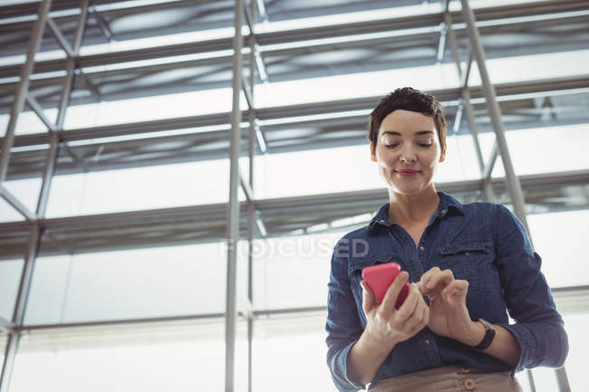 Бізнес-леді, використовуючи мобільний телефон в зоні очікування в терміналі аеропорту — стокове фото