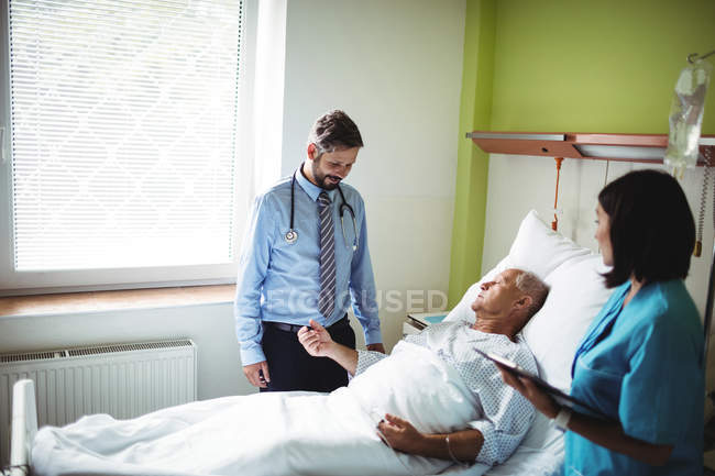 Médico e enfermeiro interagindo com o paciente no hospital — Fotografia de Stock