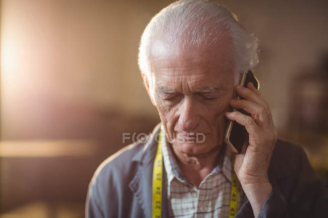 Haut cordonnier parler sur le téléphone portable dans l'atelier — Photo de stock