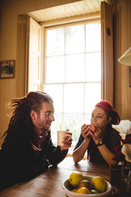 Feliz jovem casal tomando café à mesa em casa — Fotografia de Stock